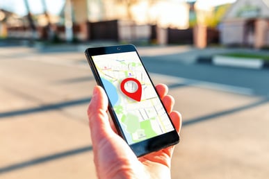 a financial advisor holding up a smart phone with a location identifier on the screen