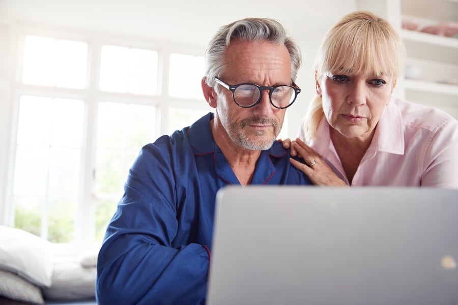 baby boomer man and woman staring at an open laptop researching financial advisors